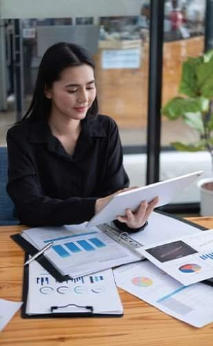 Home 2 A woman reviews a digital tablet at a desk with charts and graphs